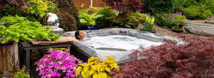 Lady relaxing in hot tub surrounded by lush garden plants